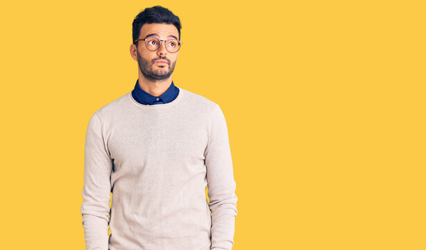 Young handsome hispanic man wearing elegant clothes and glasses smiling looking to the side and staring away thinking.