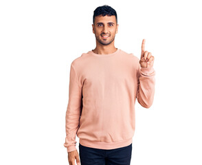 Young hispanic man wearing casual clothes showing and pointing up with finger number one while smiling confident and happy.