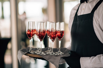 Glasses with red champagne on a tray at the waiter