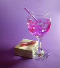a beautiful drink with hearts and a gift on a purple background. Romantic background for the Valentine's day holiday