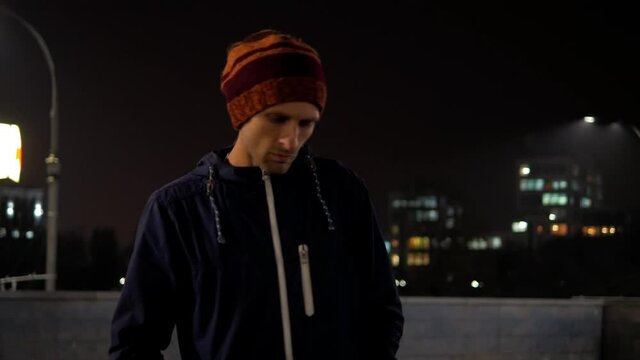 Sad Man Walking In Night Street With City Lights Background