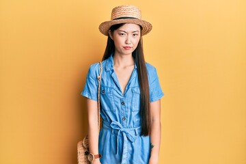 Young chinese woman wearing summer hat skeptic and nervous, frowning upset because of problem....