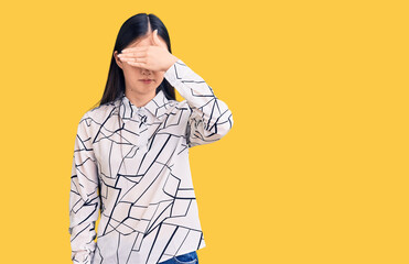Fototapeta premium Young beautiful chinese woman wearing casual shirt covering eyes with hand, looking serious and sad. sightless, hiding and rejection concept