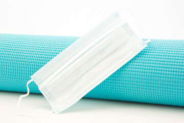 Blue yoga mat with medical mask reflect fitness and exercise essentials and rules for gyms and...