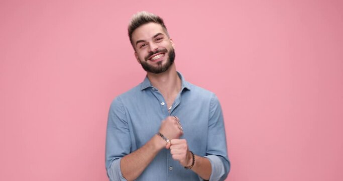 excited casual man celebrating succes, mocking someone and framing against pink background