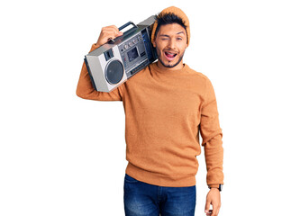 Handsome latin american young man holding boombox, listening to music winking looking at the camera...