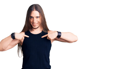 Young adult man with long hair wearing goth style with black clothes looking confident with smile...