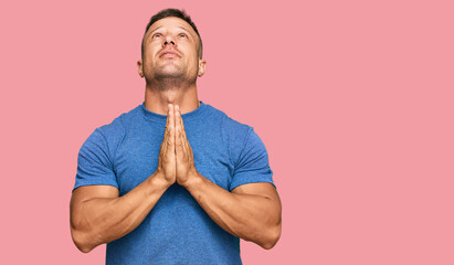 Handsome muscle man wearing casual clothes begging and praying with hands together with hope...
