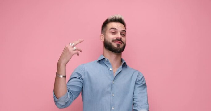 attractive casual man gesturing that the boredom is killing him against pink background