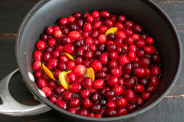 Making Cranberry Sauce: Boiling cranberries, cloves, and orange zest in a saucepan