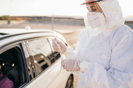 Doctor Doing A PCR Test COVID-19 On A Patient Through The Car Window. PCR Diagnostic For Coronavirus Presence,doctor In PPE Holding Test Kit