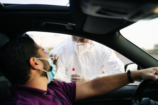 Doctor doing a PCR test COVID-19 on a patient through the car window. PCR diagnostic for Coronavirus presence,doctor in PPE holding test kit