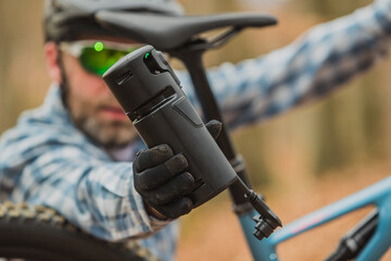 Person holding a battery pack, an extender for an electric mountain bicycle.