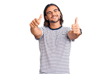 Young handsome man wearing casual clothes approving doing positive gesture with hand, thumbs up smiling and happy for success. winner gesture.