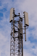 Tower with 5G and 4G cellular network antenna on blue cloudy sky background.