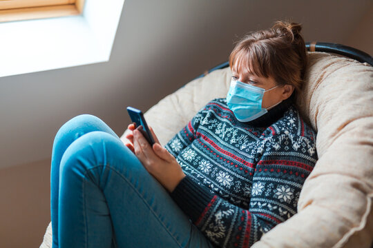 The woman is in self isolation in the house. The woman is very emotionally talking on the phone sitting in a chair.