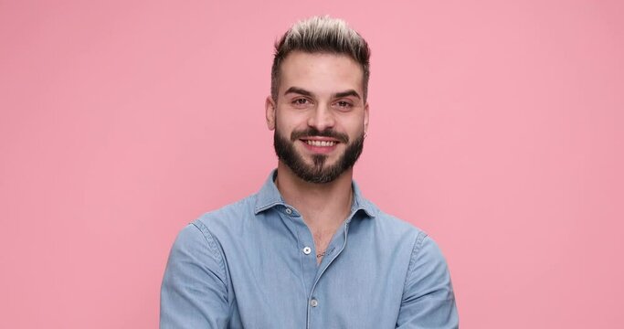 young sexy casual man laughing, winking and flirting on pink background