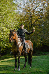 A black horse and a a man on a sunny autumn day.