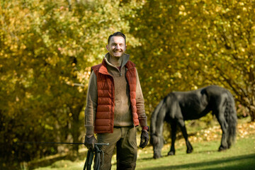 A black horse and a a man on a sunny autumn day.