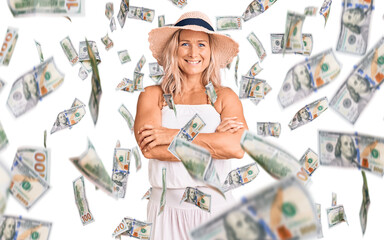 Middle age fit blonde woman wearing summer hat happy face smiling with crossed arms looking at the camera. positive person.