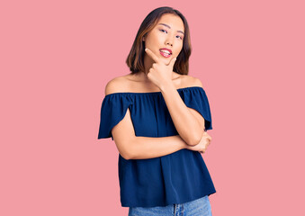 Young beautiful chinese girl wearing casual clothes looking confident at the camera smiling with crossed arms and hand raised on chin. thinking positive.