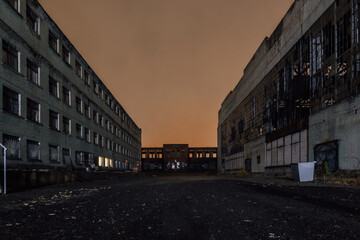 Territory of abandoned industrial area waiting for demolition at night. Broken and burnt buildings
