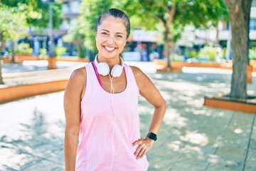 Middle age sportswoman smiling happy  wearing headphones at the park