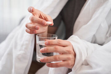 Man holding a pill over a glass of water