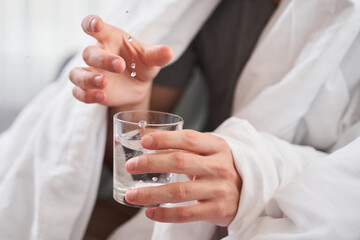 Man throwing a pill into a glass of water
