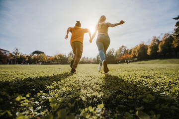 Young happy couple running on a green meadow - Focus on the grass