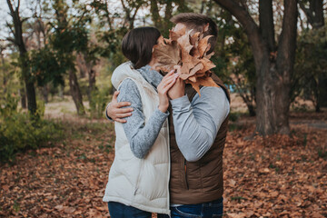 couple in love hidden behind an autumn bouquet of leaves