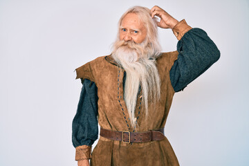 Old senior man with grey hair and long beard wearing viking traditional costume confuse and...