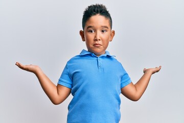 Little boy hispanic kid wearing casual clothes clueless and confused expression with arms and hands raised. doubt concept.