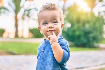 Cute and happy little boy having fun at the park on a sunny day. Beautiful blonde hair male toddler playing outdoors