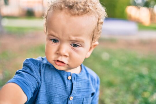Cute and sad little boy crying having a tantrum at the park on a sunny day. Beautiful blonde hair male toddler frustrated with tears on face outdoors