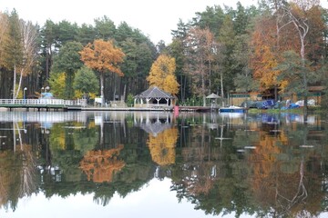 Fototapeta premium Pier and holiday resort on the lake by the forest in beautiful autumn scenery. Lapino Lake, Kashubia, Poland