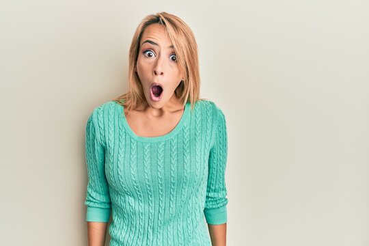 Beautiful blonde woman wearing casual winter sweater afraid and shocked with surprise expression, fear and excited face.