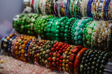 Gemstone bracelets and necklaces in a row. Jewelry made of blue agate crystal, mountain quartz, red coral stones, tiger eye stones. Healing, powerful crystal energy. Esoteric and colorful background.