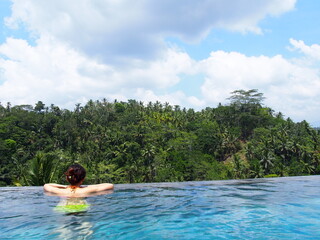 A woman relaxing in the infinity pool with a spectacular view, Ubud, Bali, Indonesia