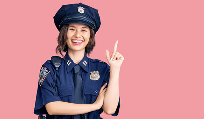 Young beautiful girl wearing police uniform with a big smile on face, pointing with hand and finger to the side looking at the camera.