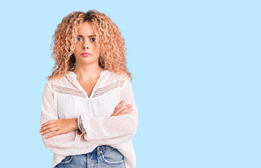 Young blonde woman with curly hair wearing elegant summer shirt skeptic and nervous, disapproving...