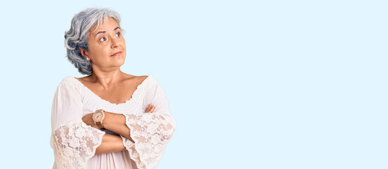 Senior woman with gray hair wearing bohemian style looking to the side with arms crossed convinced and confident