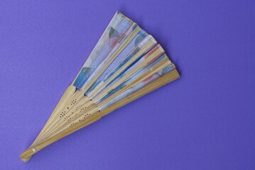 one old brown wooden fan with colored cloth lies on a lilac table