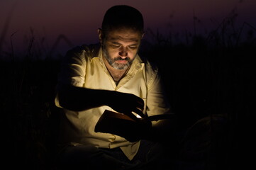 man in a dark environment reading a book