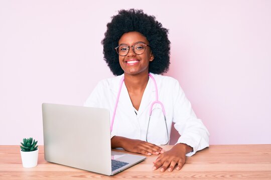 Young african american woman wearing doctor stethoscope working using computer laptop looking positive and happy standing and smiling with a confident smile showing teeth