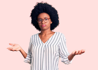Young african american woman wearing casual clothes and glasses clueless and confused expression...