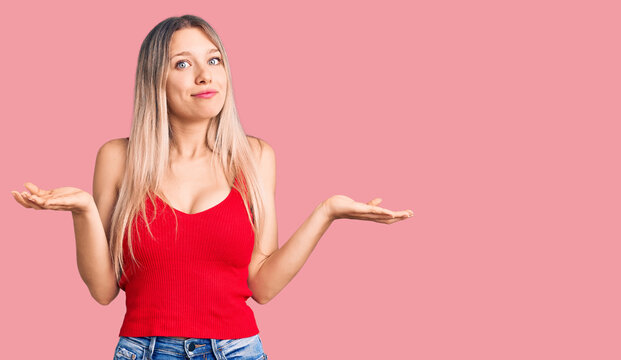 Young beautiful blonde woman wearing casual clothes clueless and confused expression with arms and hands raised. doubt concept.