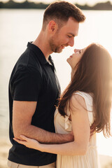 Romantic couple is hugging outdoors. elegant and stylish woman and man in love are walking along the lake. Happy moments together. love story