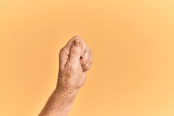 Senior caucasian hand over yellow isolated background holding blank space with thumb finger,...