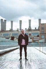 Handsome casual man in windbreaker standing on a the soaring bridge industrial background. © Northern life